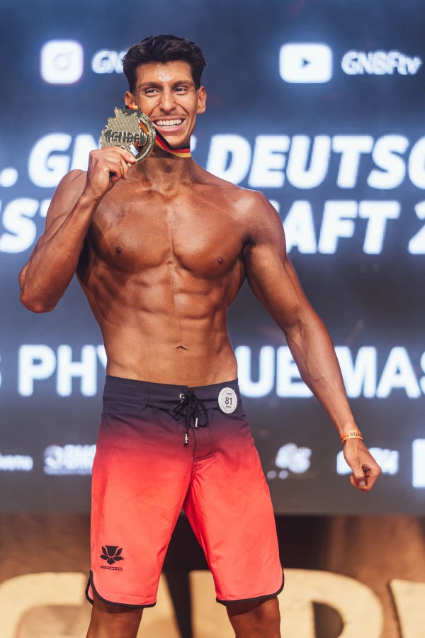 Yussef Jaber mit Medaille um den Hals, hält die Medaillenplatte lächelnd in die Höhe