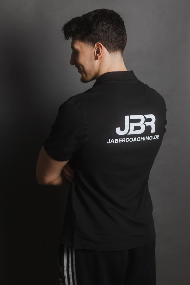 Yussef Jaber zeigt das JBR Jaber Coaching Logo auf seinem Polo-Shirt